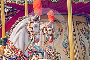 Old French carousel in a holiday park. Three horses and airplane on a traditional fairground vintage carousel. Merry-go-round with