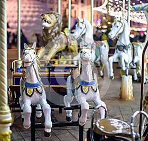 Old French carousel in a holiday park. Three horses and airplane on traditional fairground vintage . Merry-go-round with .