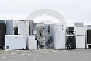 Old fridges freezers refrigerant gas at refuse dump skip recycle stacked pile plant help environment reduce pollution white silver