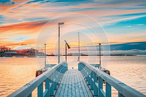 Old Frosted Wooden Boards Pier On Calm Water Of Lake Or River Or Sea At Evening Or Morning Time. Sunset Sunrise In