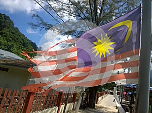 Old full of holes Malaysian flag waving on the wind