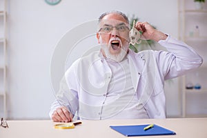 Old funny male zoology teacher demonstrating fish skeleton