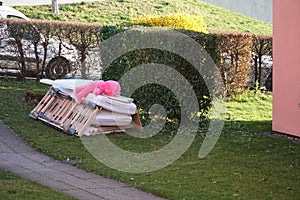 Old furniture disjointed on a pile on the lawn with a big pink teddy bear lying prone on it