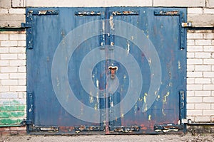 Old garage with lock and metal door. Rusty old metal texture with remnants of the paint.