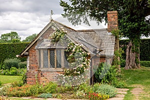 Old garden house with slate roof and climbing rose.