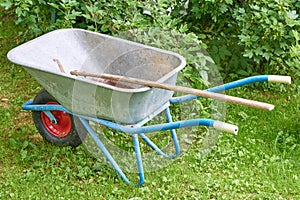 Old garden iron cart in the garden on a green lawn with a shovel photo