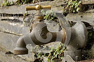 An old garden tap against a truly ancient wall.