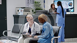 Old general practitioner taking notes at consultation with patient