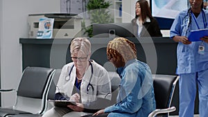 Old general practitioner taking notes at consultation with patient