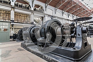 old generator on powerhouse. bottom view on big black iron electric installation with flywheel and cables in power plant