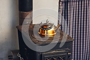 Old gilded kettle on an iron stove