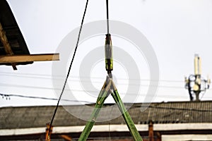 Old girder crane with large iron hook lifts  heavy load on  slings