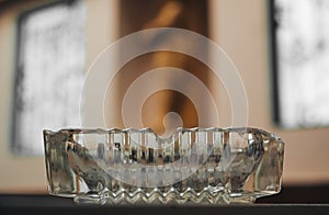 Old glass ashtray on the table on blur wall background, Vintage, dark, copy space