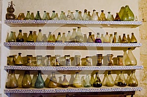 Old glass bottles and flasks on four shelves in the apothecary of the monastery of Santo Domingo de Silos, photo