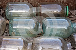 Old glass cylinders of three liters stacked in rows