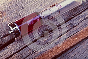 Old glass syringe on the grunge wooden surface