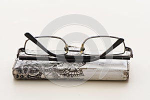 Old glasses resting on a mobile phone with an old and tacky case on a white background that isolates the objects