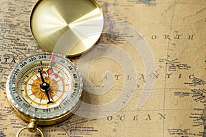 The old gold compass with cover on vintage map, macro background