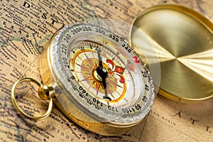 The old gold compass with cover on vintage map, macro background