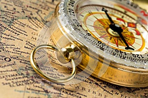 The old gold compass with cover on vintage map, macro background