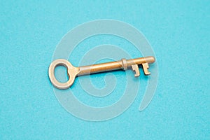 Old gold key isolated on blue background with copy space