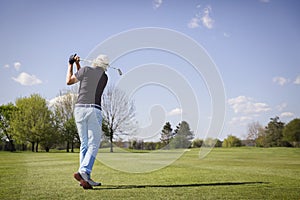 Old golfer shooting on green.