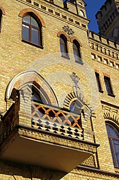 Old gothic castle balcony on yellow brick wall with arched windows