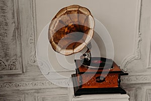 Old gramophone with horn speaker stands against anicent background, produces songs recorded on plate. Music and nostalgia concept. photo