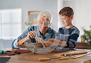 Old grandfather and child assembling wooden plane together