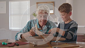 Old grandfather and child assembling wooden plane together