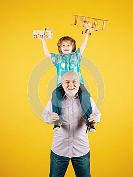 Old grandfather and young child grandson with toy plane and wooden toy truck. Men generation granddad and grandchild.