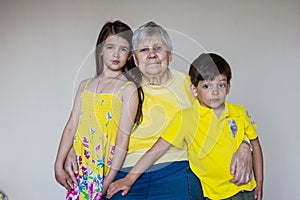 Old grandmother and her beloved grandchildren sit at home