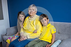 Old grandmother and her beloved grandchildren sit at home and relax in a room