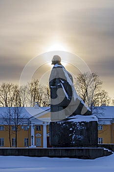 Old granite monument to Lenin on city square on short winter day