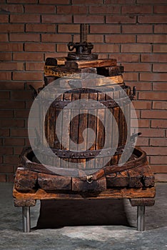 Old grape press machine wooden barrel on a brick wall background. Homemade ecological wine production on the farm