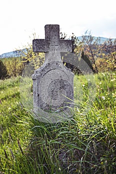Old grave on traditional European cemetery in Slovakia. Aged cross tomb stone on grave yard in spring