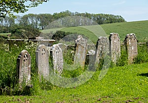 Old gravestones in a row in the graveyard at St Peter`s Church in Rodmell near Lewes in East Sussex UK.