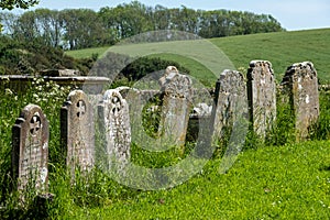 Old gravestones stand in a row in the graveyard at St Peter`s Church in Rodmell near Lewes in East Sussex, UK.