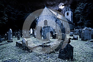 Old graveyard with ancient tombstones grave stone and old church front of full moon black raven dark night spooky horror