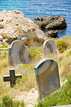 Old graveyard next to the water edge, rocks and sea of Malta