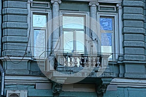 Old gray concrete balcony with windows on the wall of the building