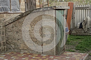 Old gray concrete cellar with green wooden door