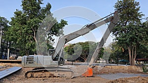 Old gray excavator with orange scoop