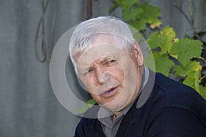 Old gray-haired man is not looking at camera