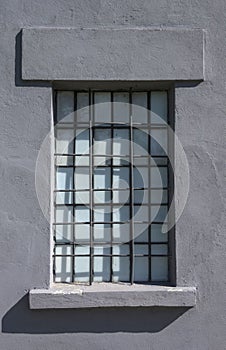 Old gray prison window with metal bars