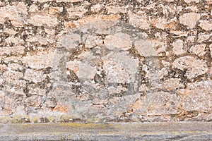 Old gray rustic stone wall facade background texture with pavement