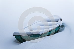 An old green boat in a frozen lake. Boat covered with pure snow
