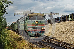 Old green diesel locomotive moving cargo train