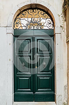 An old green door with handles in the shape of a lion`s head