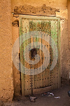 Old green door with iron lock of an adobe building in Agdz, Morocco